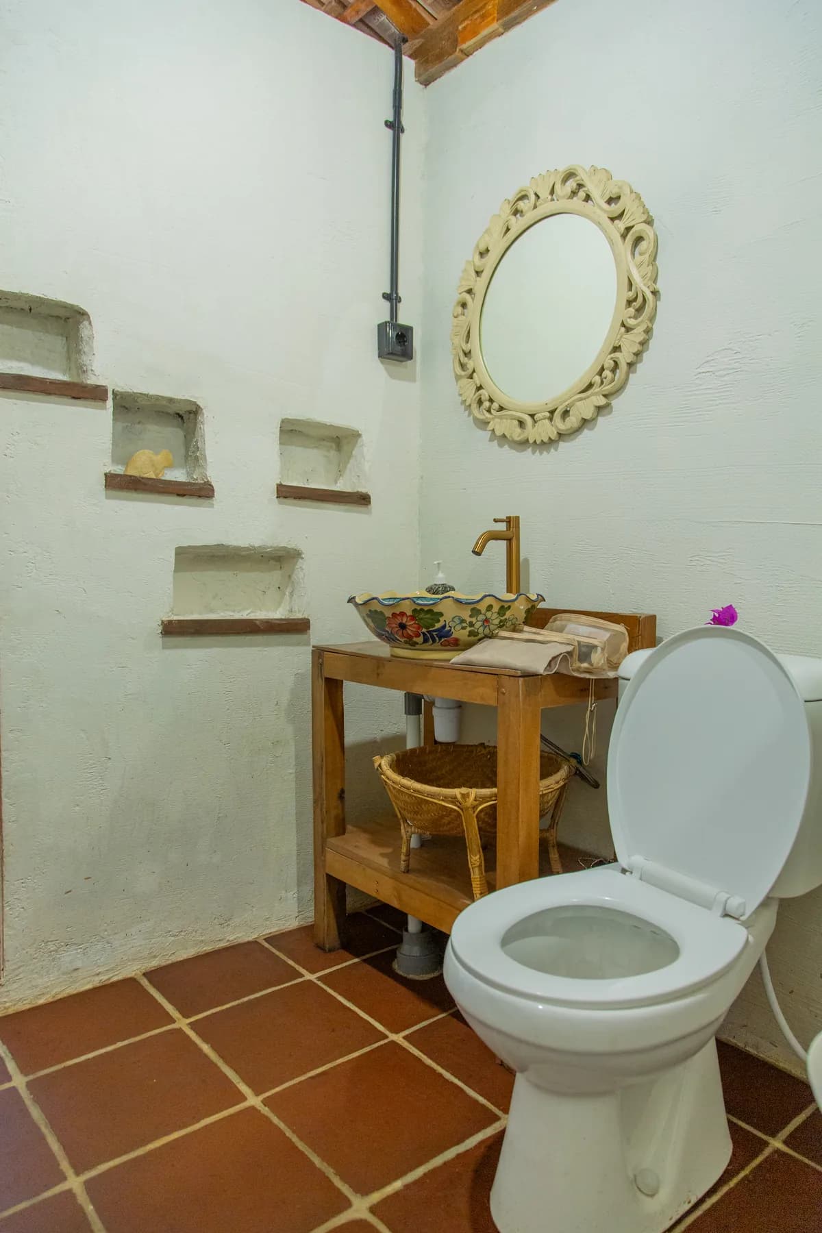 The open bathroom with a hand-painted basin and a carved mirror