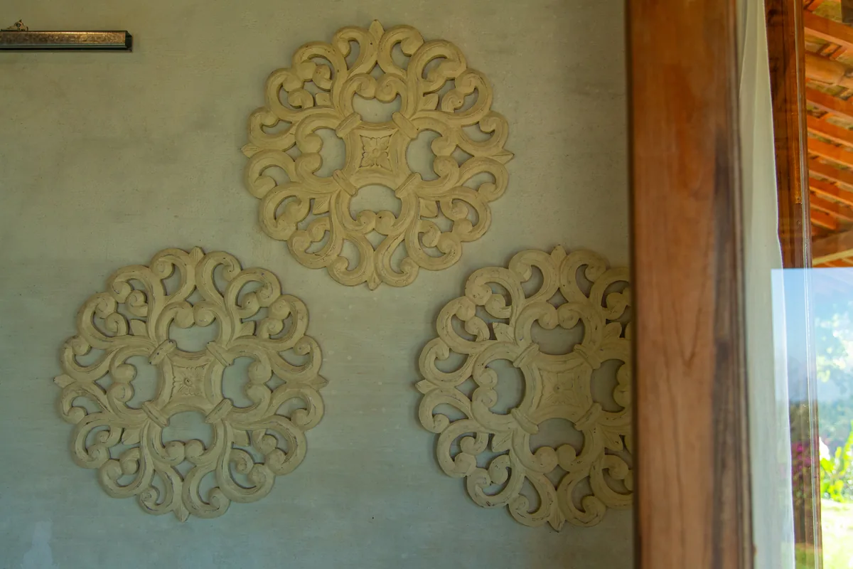 Carved wooden discs mounted on the lime-washed wall of the house