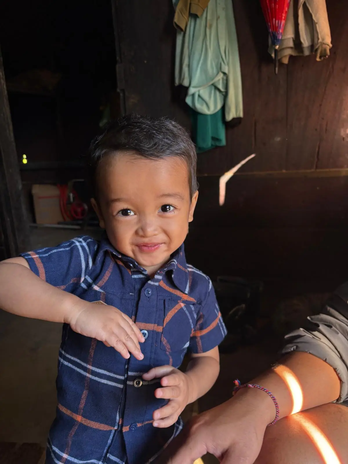 A small child standing in the doorway of the house, mid-grin