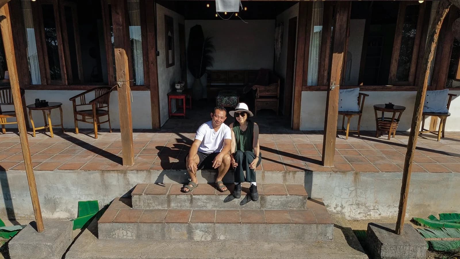 Two of the hosts sitting together on the front steps of the house