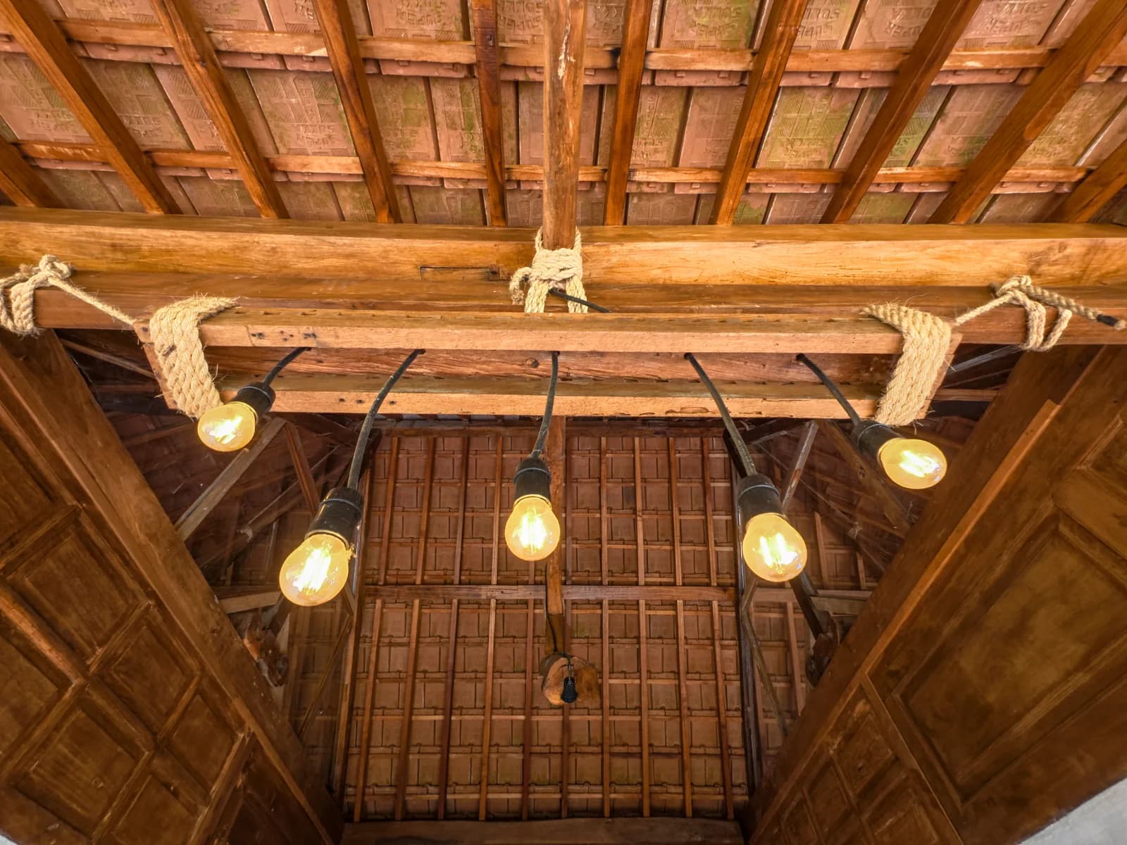 Bulbs strung from the timber rafters above the table where dinner is served