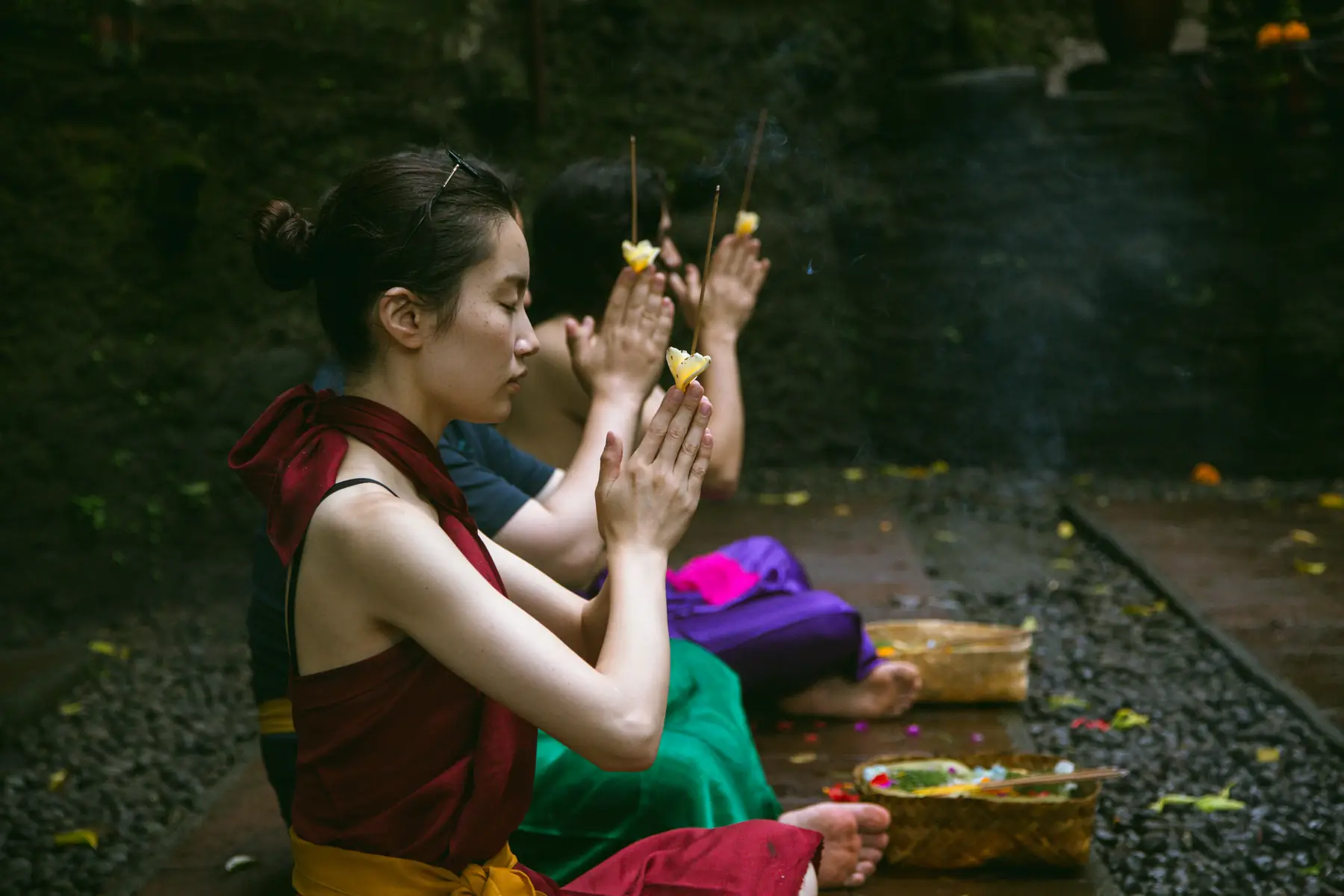 Hands raised in prayer over a palm-leaf offering