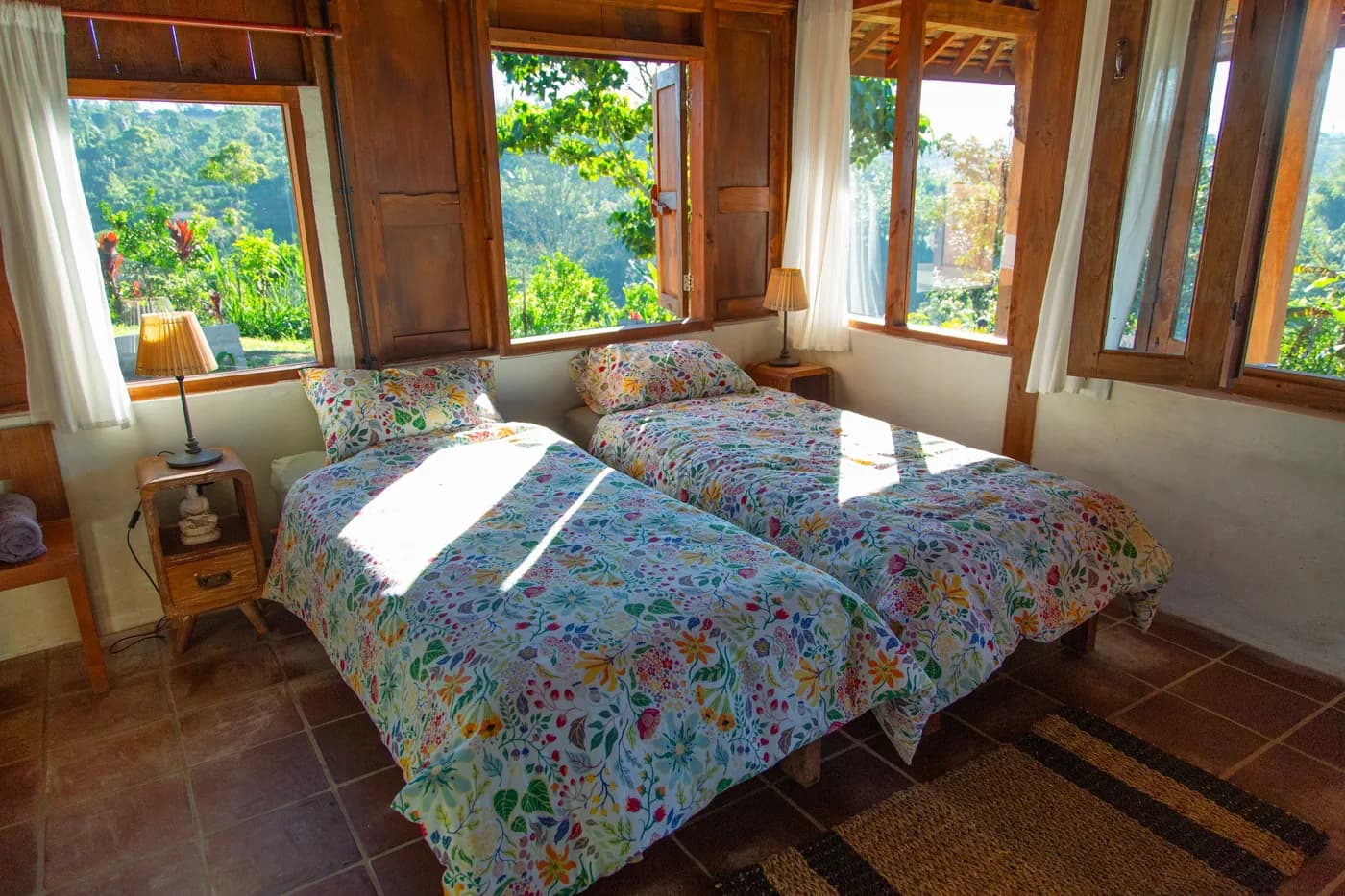 Morning light across a guest bed, with the valley visible through the corner windows